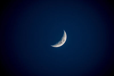 Low angle view of half moon against clear sky at night