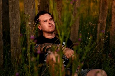 Thoughtful man looking away while sitting on field