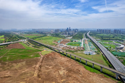 High angle view of road amidst field against sky