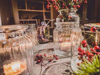 Tealights in glass jars decorated on tray with red berries 