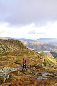 Rear view of man walking on mountain against sky