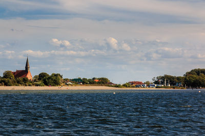 Scenic view of sea by buildings against sky