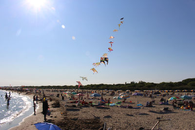 People at beach against sky on sunny day