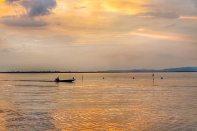 Silhouette person in sea against sky during sunset