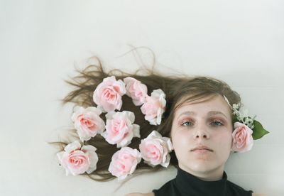 Portrait of woman with pink flowers against white wall