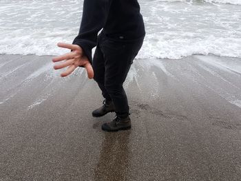 Low section of man standing on beach