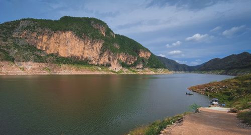Scenic view of lake by mountains against sky
