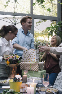 Smiling man removing gift from bag during party at restaurant