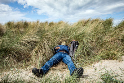 The tired city man has gone to sleep in the dunes, holding his backpack tightly