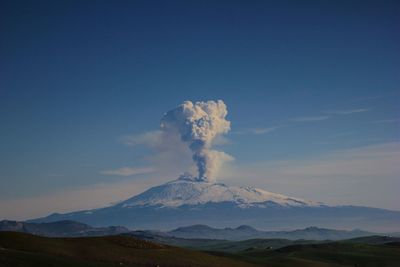 Smoke emitting from volcanic mountain against sky