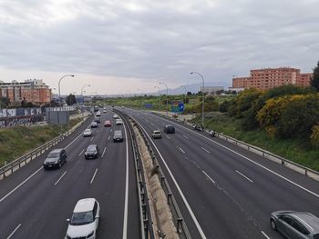 Vehicles on highway in city against sky