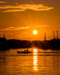 Silhouette boats in sea against orange sky