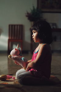 Side view of girl looking at toy at home