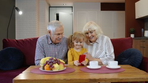 Grandparents with granddaughter looking at mobile phone
