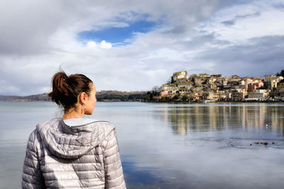 Rear view of woman looking away while standing against sea