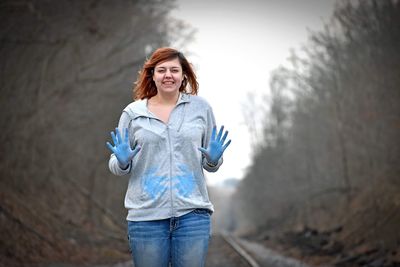 Portrait of smiling woman with powder paint covered hands against trees