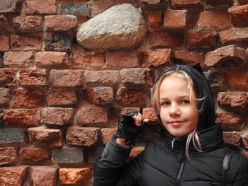 Portrait of girl against brick wall