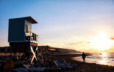 Person at beach against sky during sunset