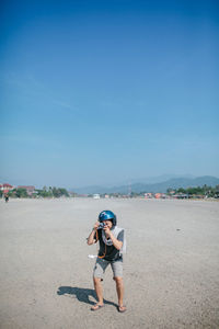 Full length of boy on road against clear blue sky