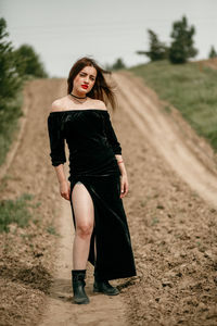 Portrait of young woman standing on dirt road