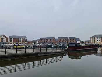 Buildings by river against sky in city