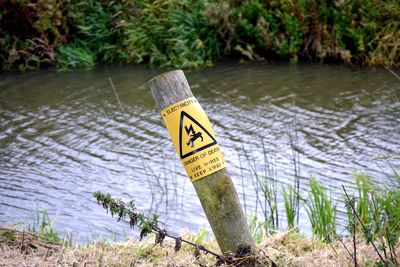 Close-up of warning sign by lake