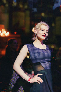 Portrait of young woman standing in city at night