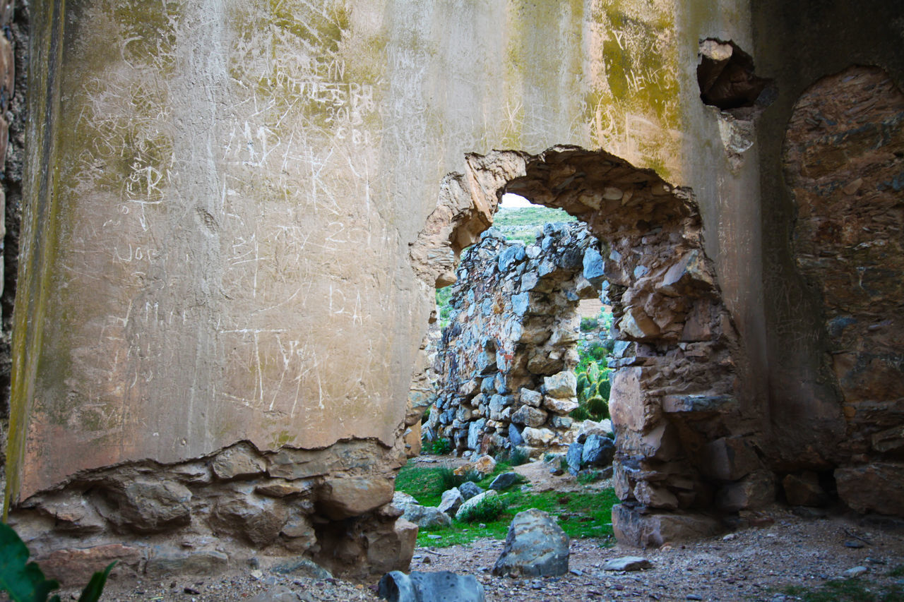 OLD STONE WALL BY ROCK FORMATION AND BUILDING