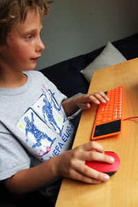 Cute boy using computer on table at home