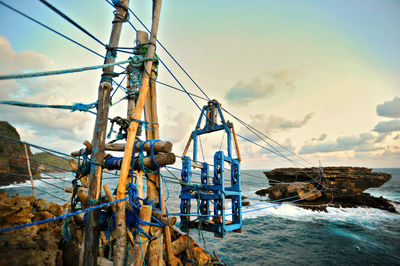 Overhead cable car hanging over sea against sky