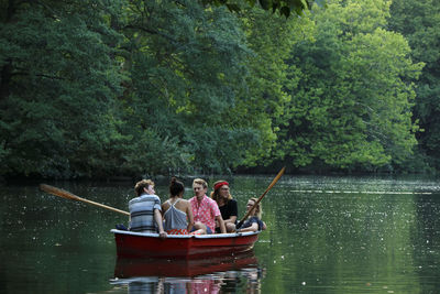 People sitting in river against trees