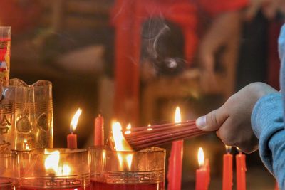 Cropped hand burning incense sticks on temple