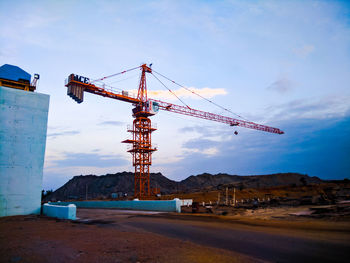 Cranes at construction site against sky