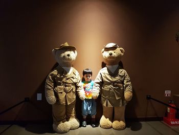 Portrait of boy standing with teddy bears against wall