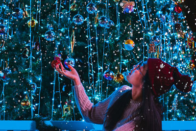 Woman holding illuminated christmas decoration at night