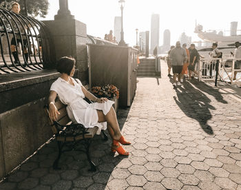 Rear view of woman sitting on sidewalk in city