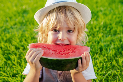 Boy holding watermelon on field