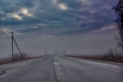 Empty road against cloudy sky