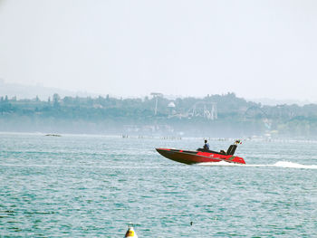 Men on boat in sea against clear sky