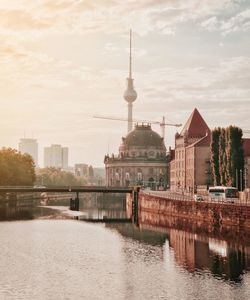 View of buildings by river against cloudy sky