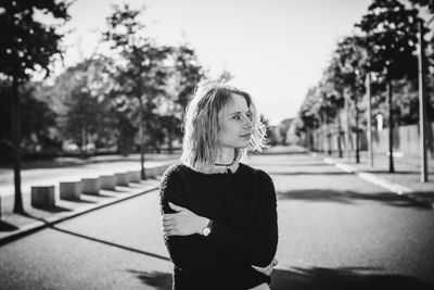 Young woman standing on road amidst trees