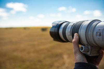 Cropped hand of person photographing against sky