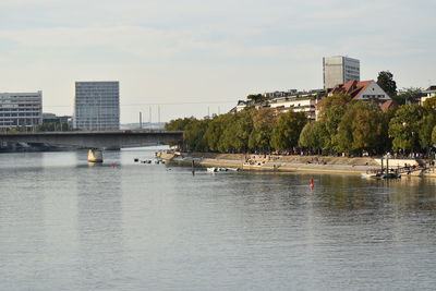 Bridge over river by buildings against sky