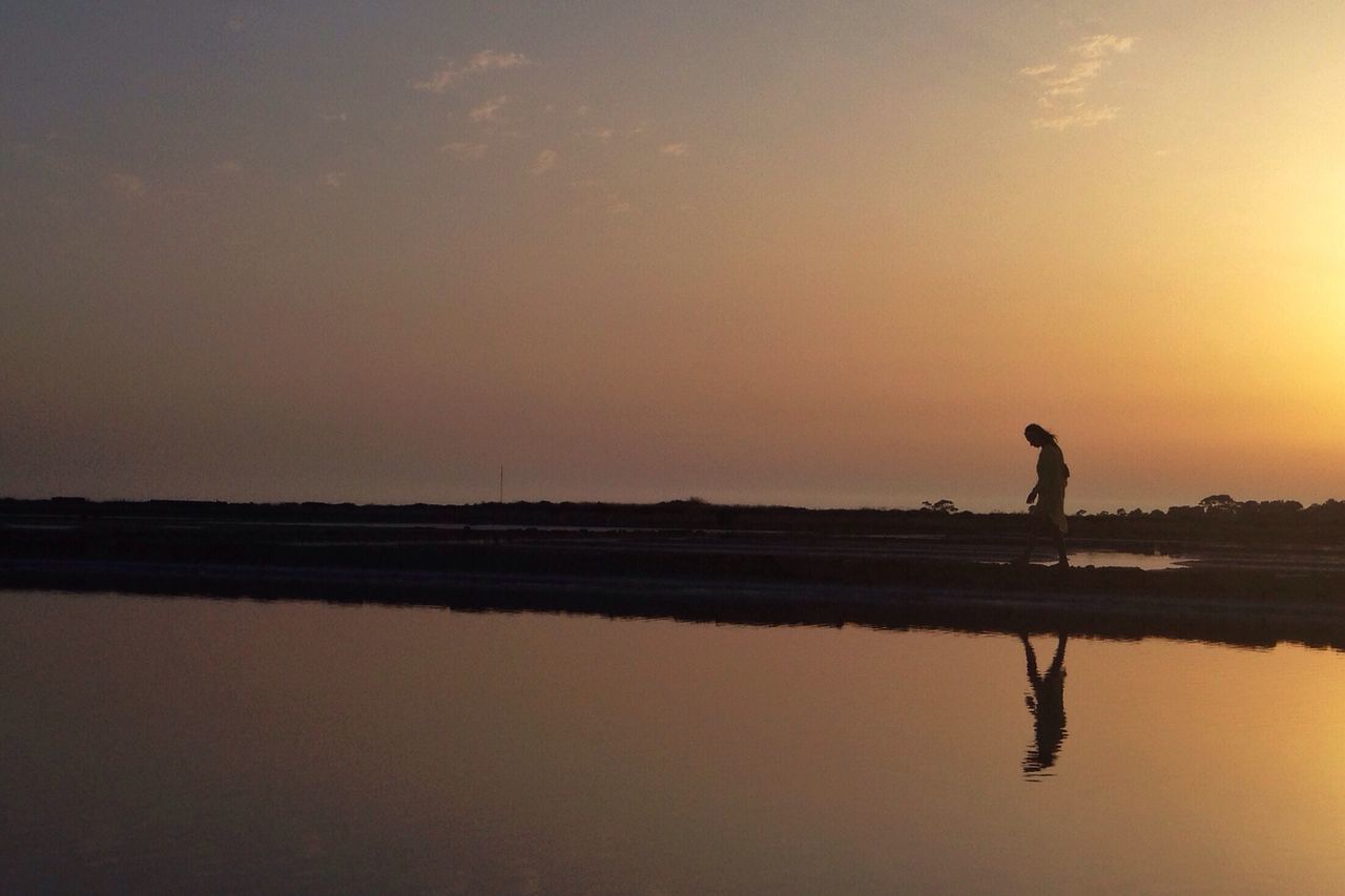 sunset, silhouette, water, reflection, tranquil scene, tranquility, scenics, lake, standing, beauty in nature, leisure activity, lifestyles, men, orange color, nature, waterfront, sky, full length