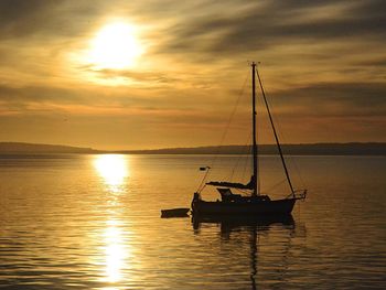 Sailboat sailing in sea at sunset