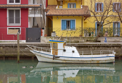 Boats moored on canal by buildings in city