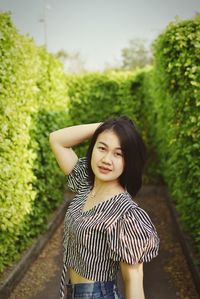 Portrait of a smiling young woman standing against plants