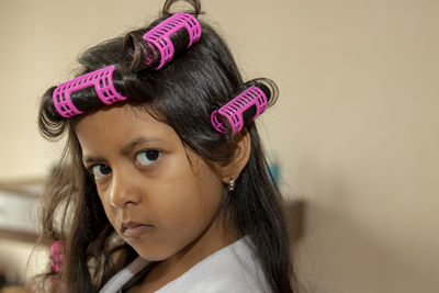 Close-up portrait of girl wearing hair curlers at home