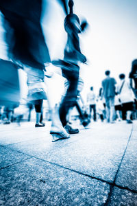 Low section of people walking on street in city