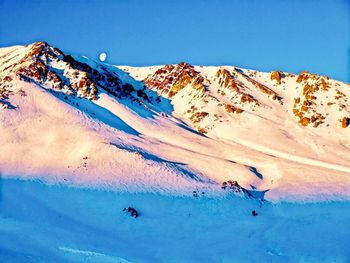 Scenic view of snowcapped mountains against clear blue sky